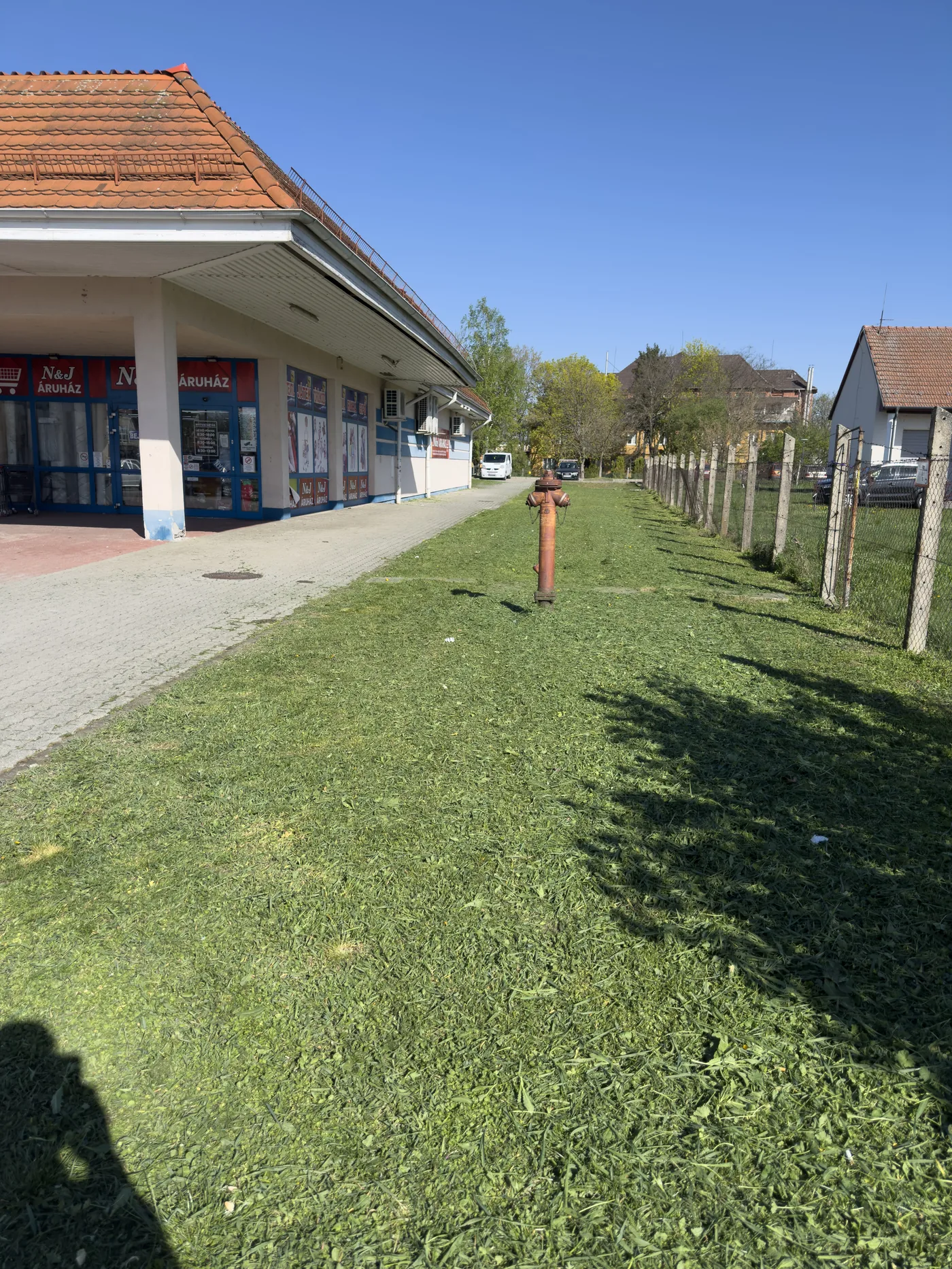 fűnyírás után – rendezett zöldterület bolt előtt Mezőkövesd | Tiszta Zóna